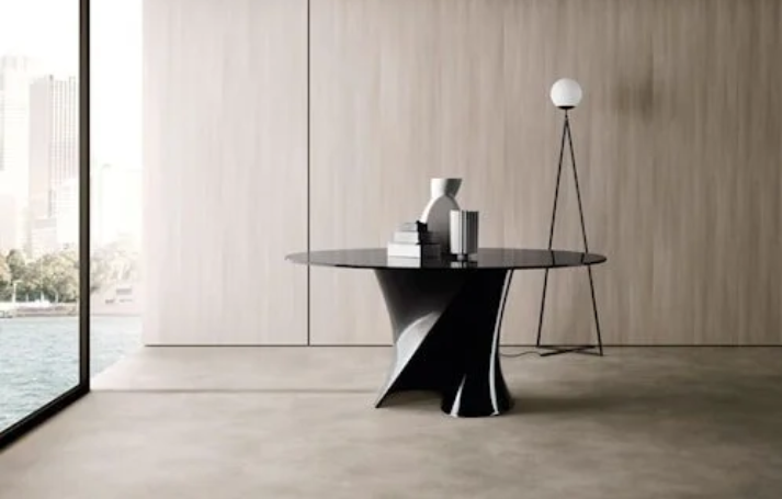 Modern S table featuring a round glossy black tabletop supported by a central twisted, sculptural S-shaped pedestal base, styled with ceramic decor accents.