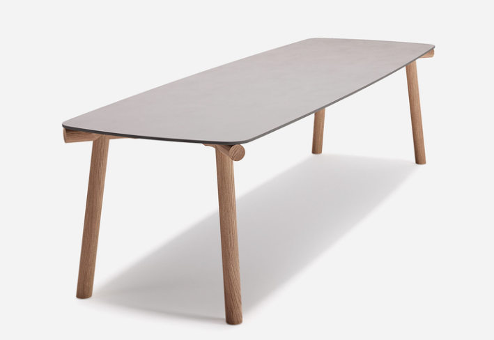 Kasumi table featuring a thin, rounded rectangular grey top supported by splayed natural wooden legs, isolated against a plain white background.