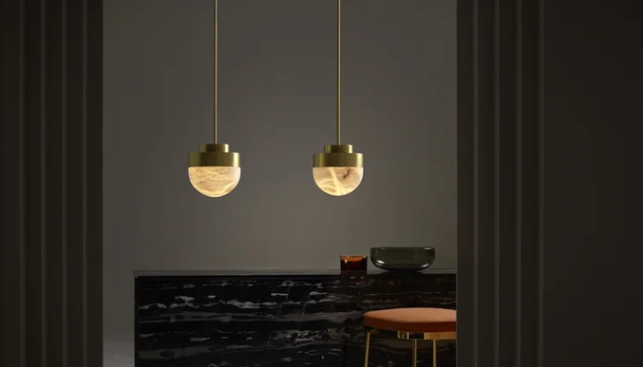 Lucid wall lamp by CTO Lighting in honed alabaster and satin brass mounted on the wall, casting a soft ambient glow.