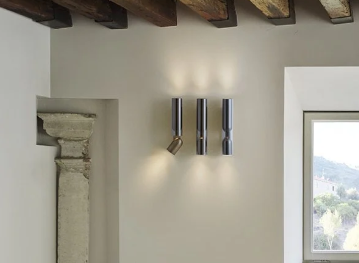 Clash Wall Lamp by Penta featuring a metal frame with a glass diffuser mounted on a contemporary living room wall, casting a soft ambient glow.