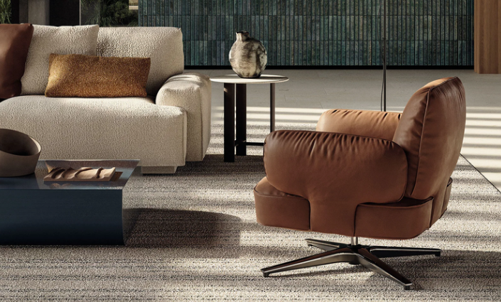 Dafne swivel lounge chair featuring cognac brown leather upholstery with plush, rounded cushions and a four-star metal base, styled on a textured rug.