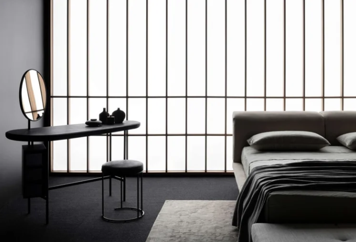 Pebble desk with a smooth, stone-inspired silhouette in lacquer finish, positioned against a wall.