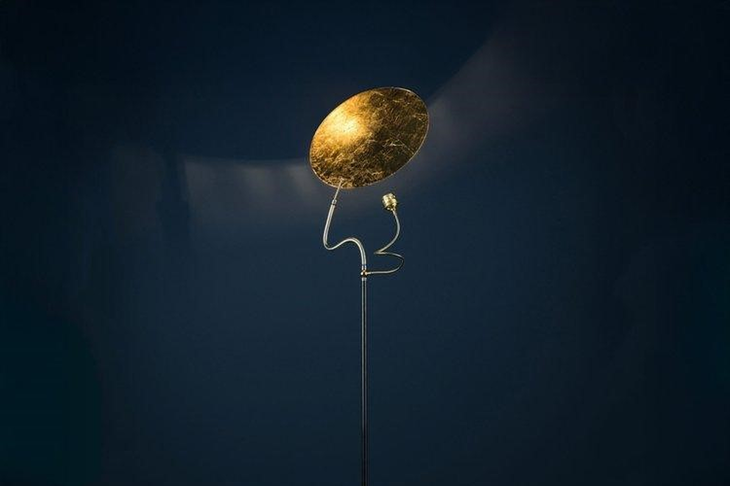 Luce d'Oro floor lamp by Enzo Catellani with rough iron base and aluminum disc diffuser on a neutral interior floor.