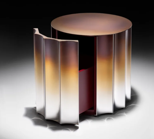 Dorica nightstand featuring a cylindrical form with fluted metallic doors in a warm gradient finish, shown with one door open to reveal a dark interior storage compartment.