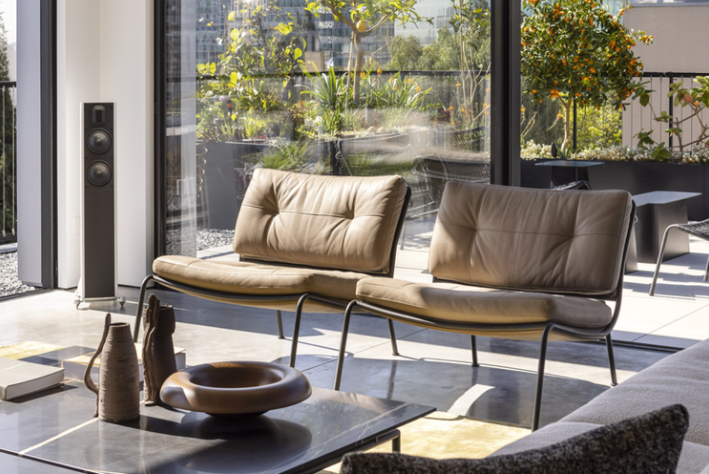 Two beige Frog lounge chairs by Piero Lissoni with removable leather or fabric upholstery placed near floor-to-ceiling glass doors