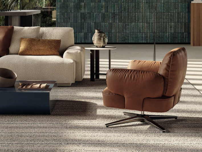 The Dafne lounge chair designed by Gordon Guillaumier in rich tan leather featuring plush armrests and a four-star swivel base, styled in a luxury contemporary living room.
