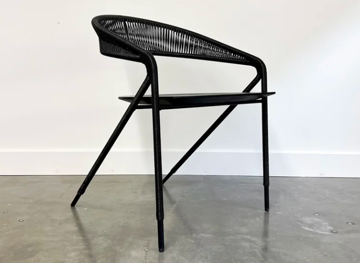 Modern black woven Georges dining chair featuring an architectural metal frame with a curved, open-slat backrest and slim, angled legs.