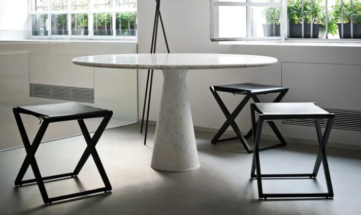 Modern M table featuring a round white marble top resting on a central conical pedestal base