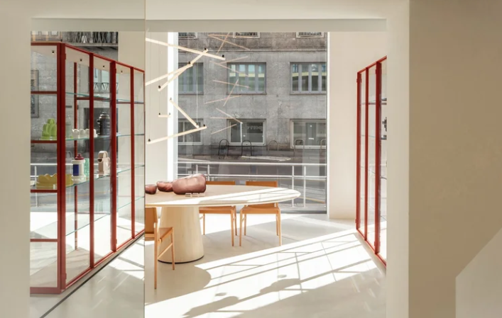 Ex-Libris glass display cabinet featuring a bold red metal frame and transparent shelves, styled in a bright showroom environment.