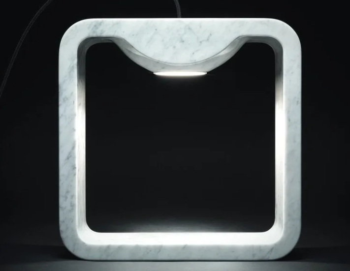 Quattrolati table lamp featuring a rounded square white Carrara marble frame with an integrated downward-pointing LED light source.