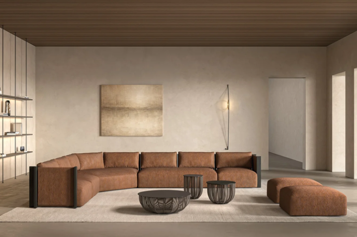 Arkadius modular sectional sofa in cognac brown leather, paired with matching ottomans and round coffee tables in an elegant, neutral-toned contemporary living space.