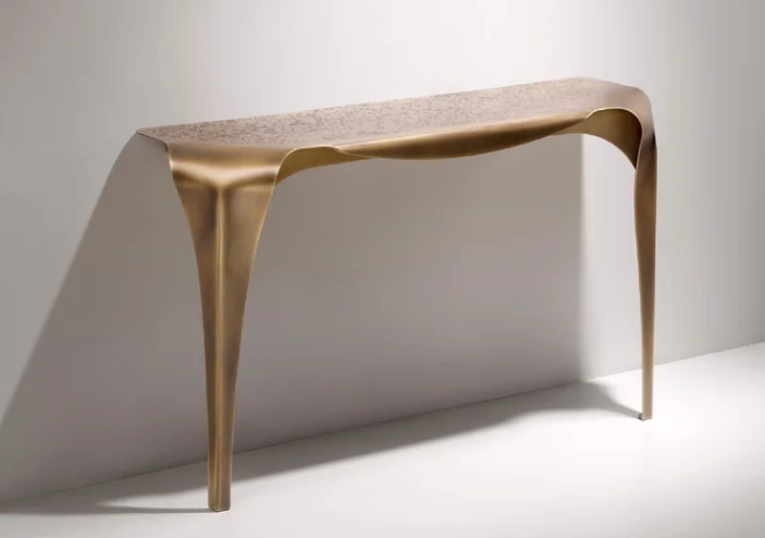 Sculptural Convivium console table featuring a fluid metallic bronze finish with a textured surface and organic tapering legs, wall-mounted against a white background.