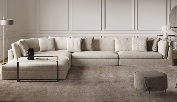 Arne sectional sofa featuring off-white fabric upholstery, low-profile modular seating, and plush accent pillows, styled with a small side table and round ottoman.