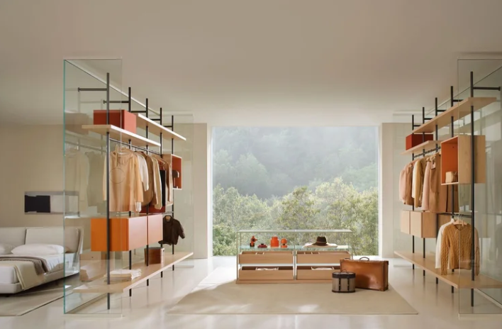 Boutique Mast shelving system featuring open modular metal posts, natural wood shelves, and orange hanging storage units, styled with hanging garments in a spacious luxury walk-in closet room.