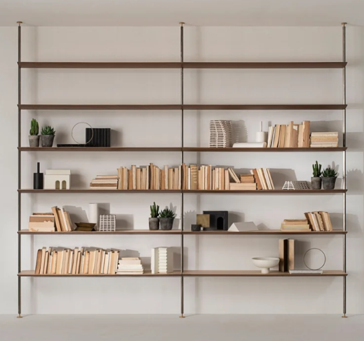 Sailor shelving system featuring floor-to-ceiling vertical steel uprights and light wood shelves, styled with books, potted succulents, and decorative objects.