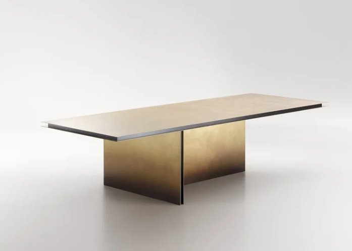 Folio dining table featuring a thin rectangular tabletop with dark edge trim supported by two intersecting brass pedestal bases with an aged patina finish, displayed on a white background.