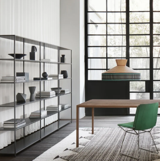 Minimalist metal shelving unit, the Minima storage system, styled with books and dark decorative objects in a modern interior.