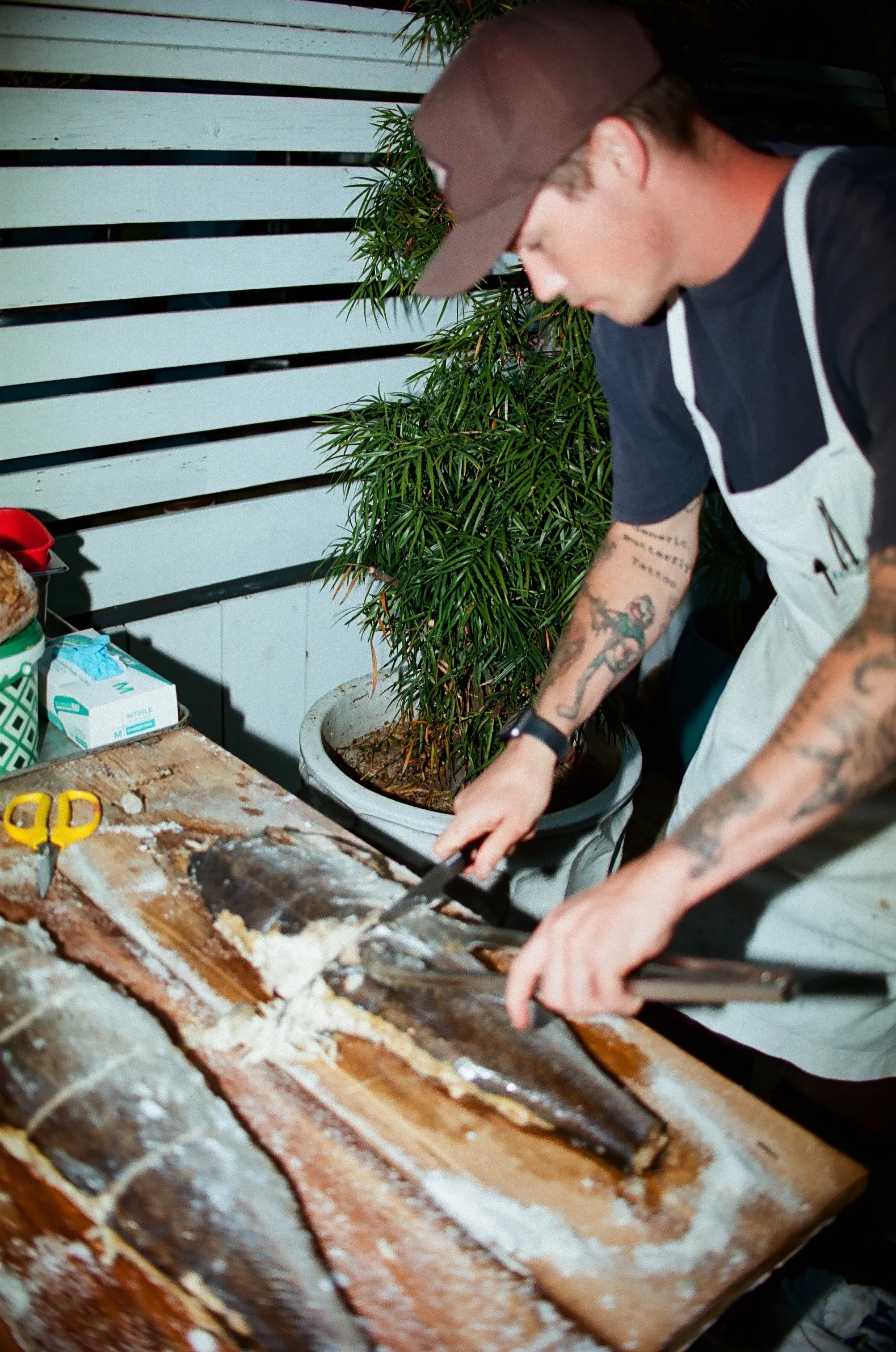 Aidan Owens expertly filleting fresh fish at Herb & Wood and Herb & Sea in San Diego, showcasing his culinary skill and commitment to local seafood.