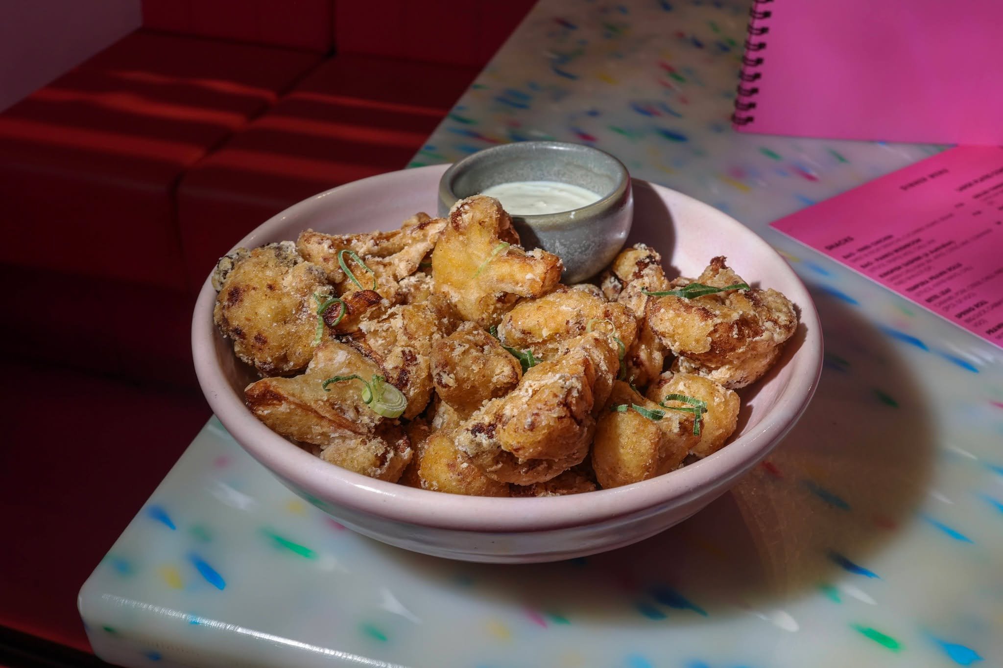 Proof that vegetables can steal the entire spotlight. Battered golden cauliflower florets tossed in fragrant seasoning and served beside tangy kaffir lime yogurt dip. Crisp on the outside, tender on the inside, and completely addictive.

Reserve your