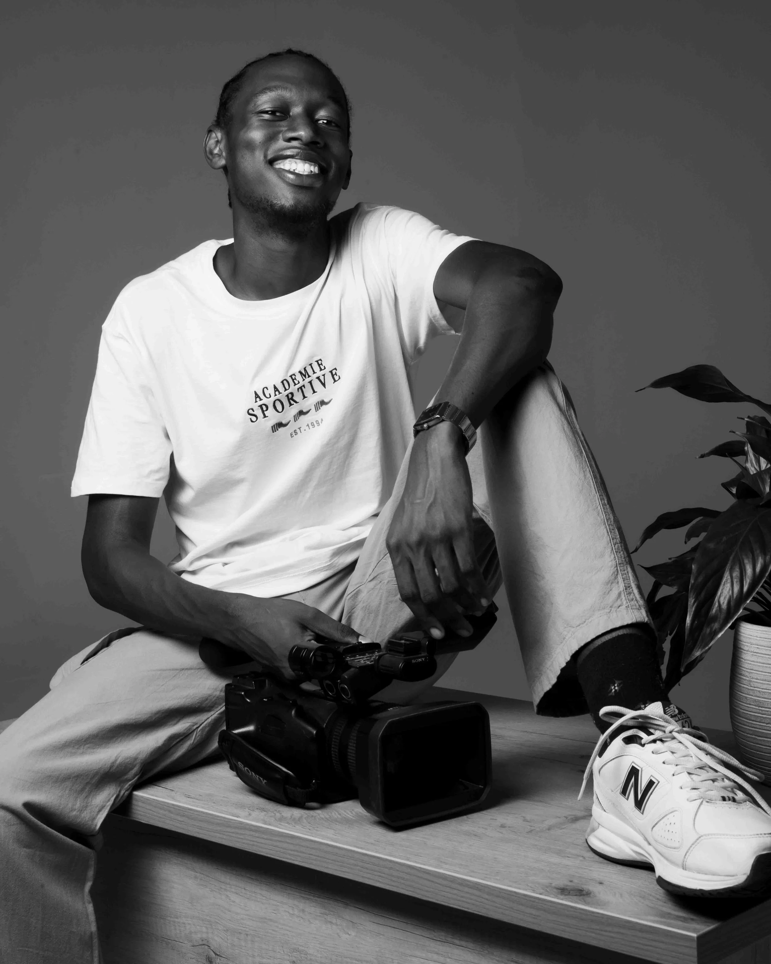 man sitting desk with one leg up and a camera on the desk