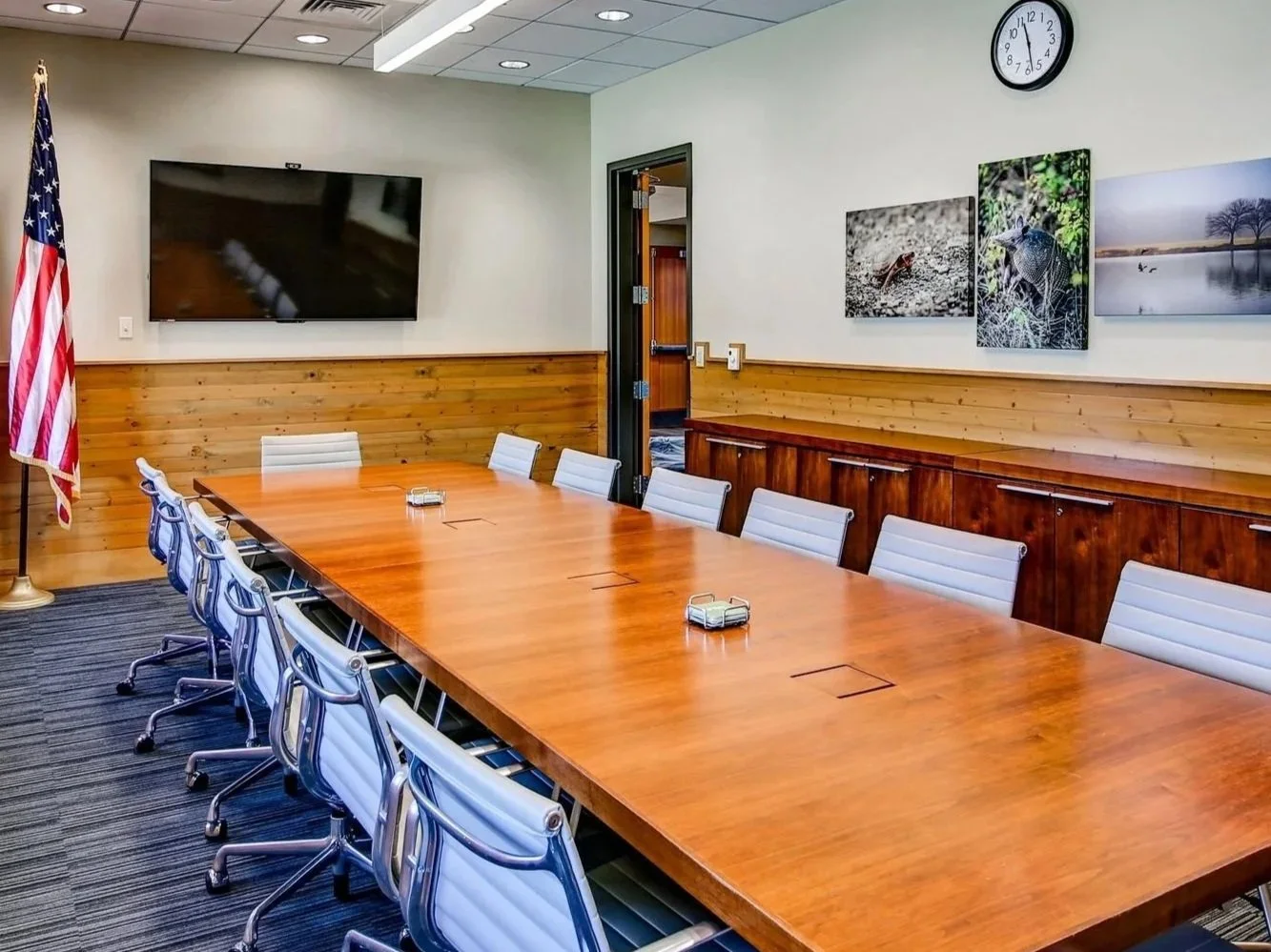 Meeting space featuring a boardroom table with chairs and a presentation screen.