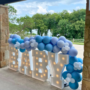 Large LED letters spelling BABY used for a Baby Shower hosted at The Nature & Retreat Center. The letters are placed along the back patio with the water and the tree line in the background