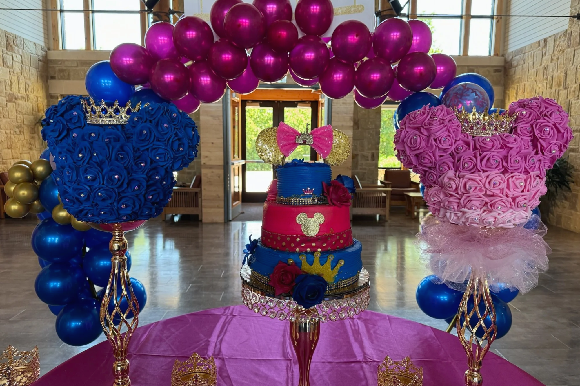 Blue and pink Baby Shower decor featuring a 3 tiered cake and balloon arch.