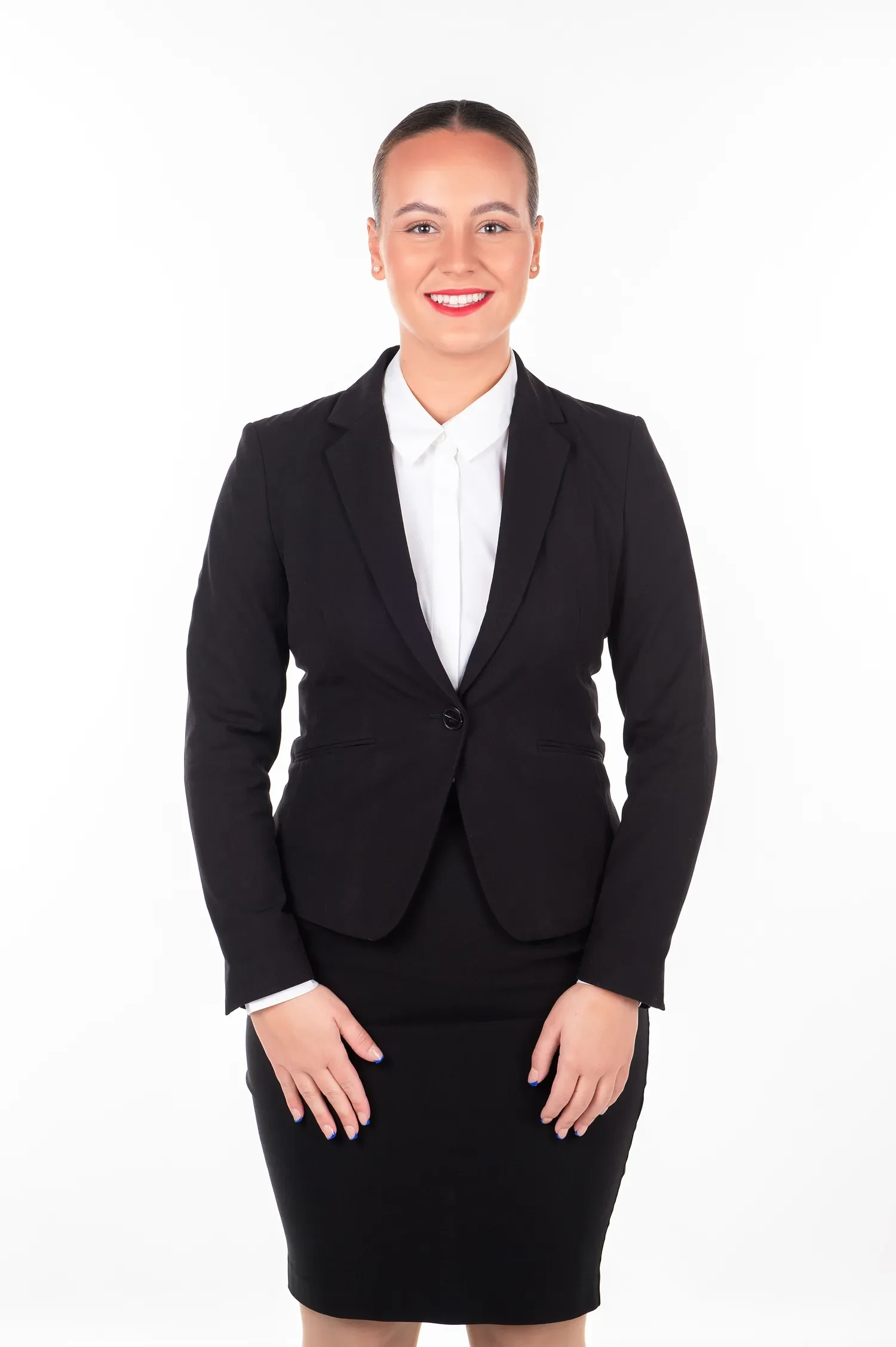 A woman in a black business suit and white shirt, smiling with red lipstick, standing against a plain white background.