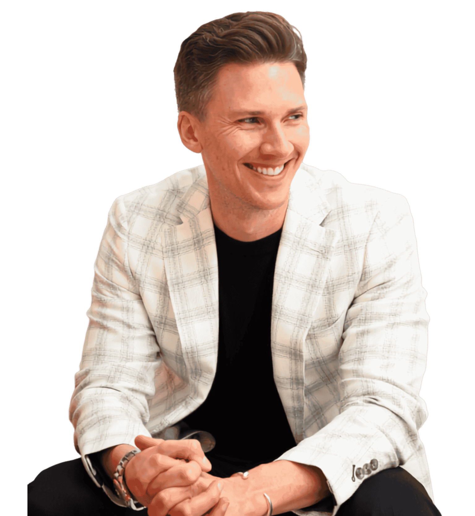 Keynote speaker Chris Rollins smiling man with brown hair, wearing a white plaid blazer and black shirt, sitting with legs crossed and hands clasped in front of him.