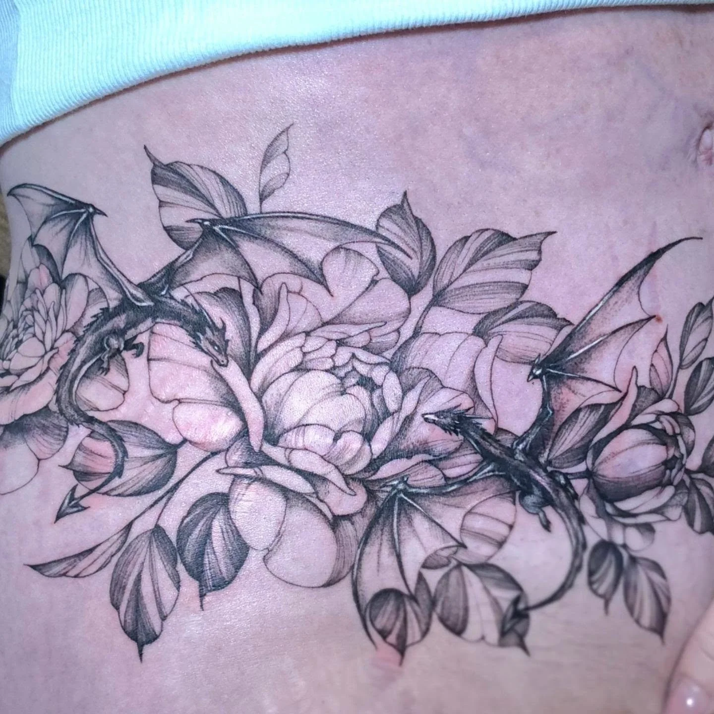 Turning scars into something new. 🖤 This scar cover-up was designed with flowing florals and tiny dragons, using the movement, layering and shading of the piece to beautifully work with the existing skin. I love how the dragons weave through the flo