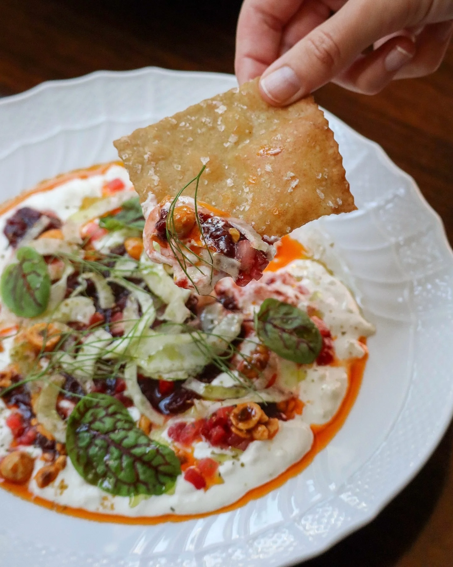 An expression of early summer, our Stracciatella arrives adorned with slow-roasted strawberries, shaved fennel, and toasted hazelnuts. Red sorrel lends vibrancy, while house-made olive oil crackers offer a crisp counterpoint to the creaminess within.