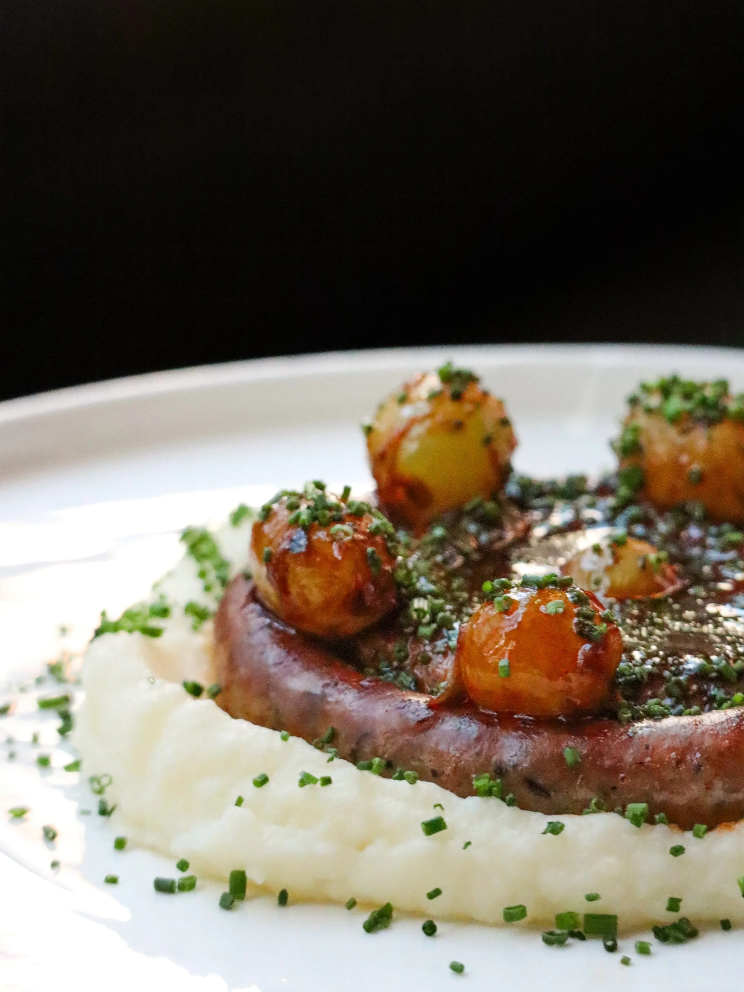 Autumn finds a delicious, hearty expression in Fennel Pork Sausage, where savory richness is punctuated by blistered grapes, softened by silken potato pur&eacute;e, and intensified with concentrated pork jus. Fresh chives finish the plate with a clea