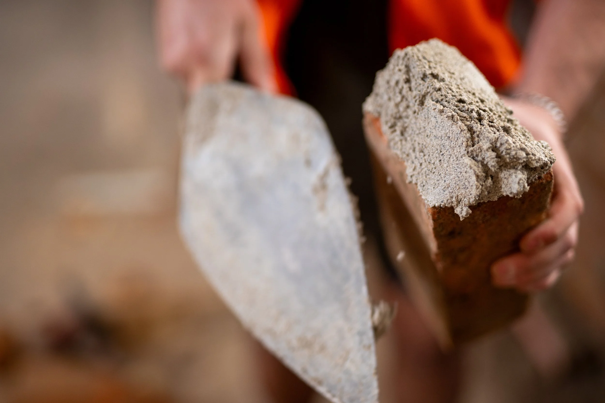Person holding two bricks, one with a rough texture and the other with a smoother surface.