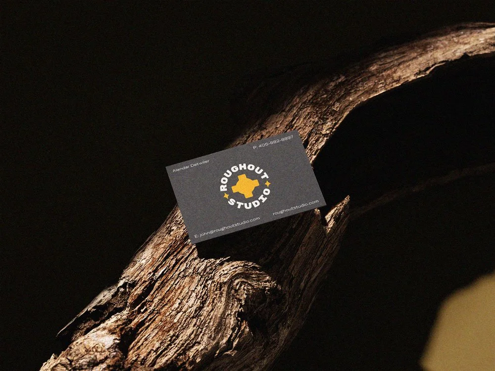 Roughout Studio, Business card for Rough Out Studio on a twisted piece of wood with dark background.