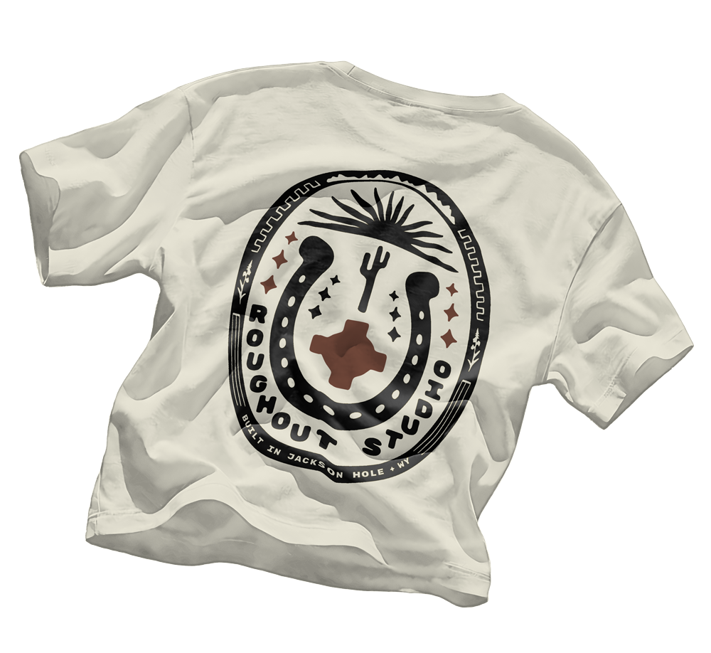 Roughout Studio, White T-shirt with a logo featuring a horseshoe, cactus, sun, and stars, and the text 'Roughhouse Stcok' and 'Built in Jackson Hole, WY'.