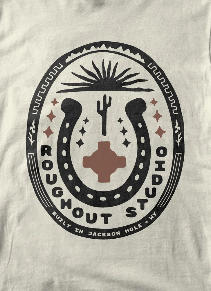 Roughout Studio, Graphic design with southwestern symbols, including a cactus, sunburst, horseshoe, and cross, with the text 'Rough Out Studio' and 'Built in Jackson Hole, WY'.