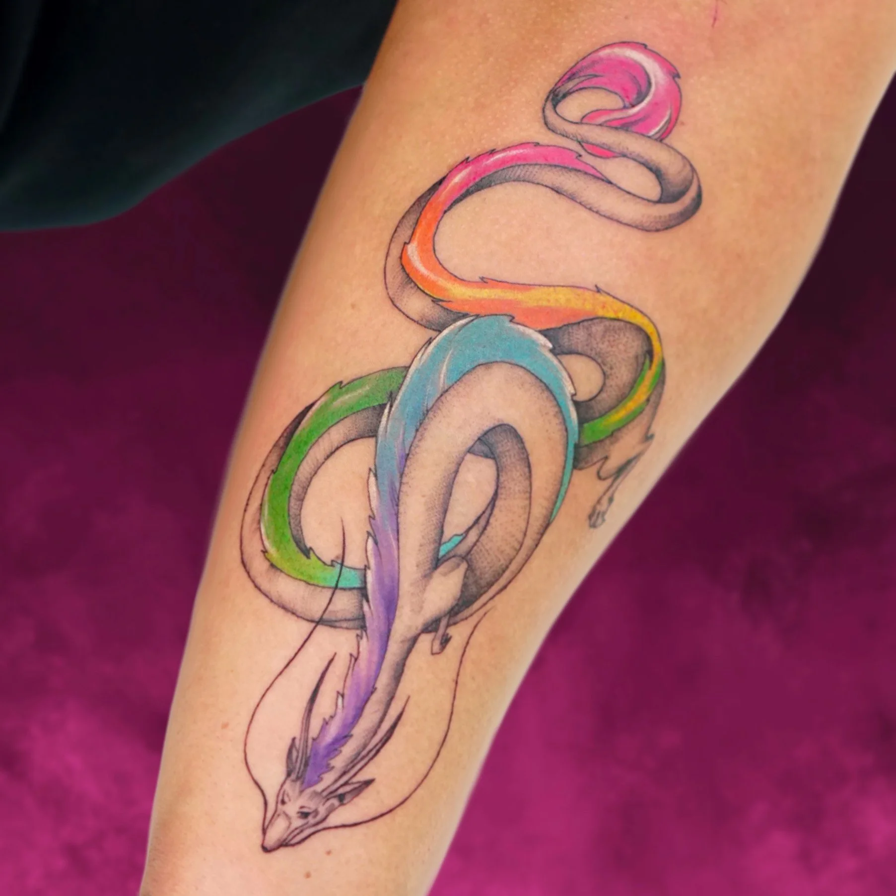 Colorful tattoo of a snake with a vibrant rainbow pattern on its body.