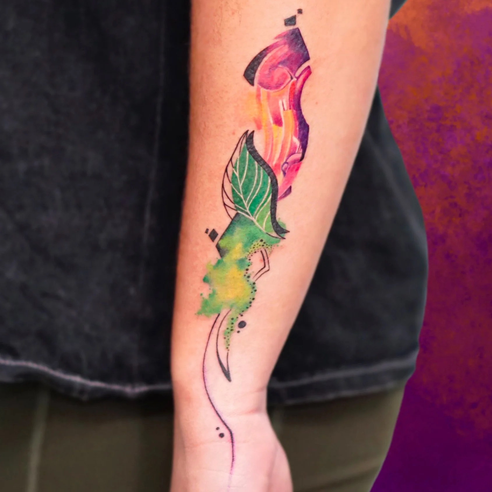 Watercolor tattoo of a leaf with decorative lines and splashes of green, yellow, and pink colors.