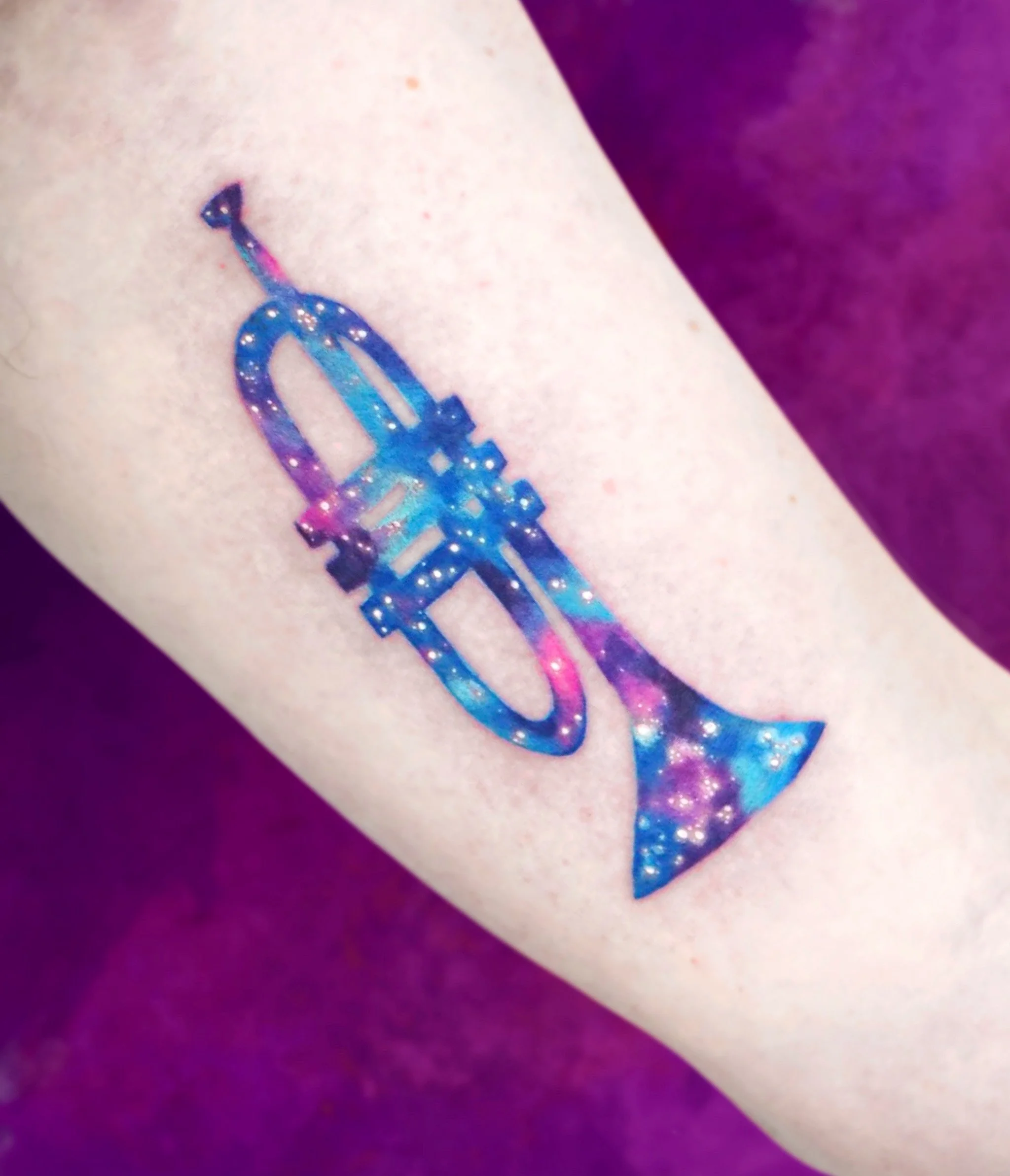 Tattoo of a spaceship with a galaxy pattern on a person's arm.