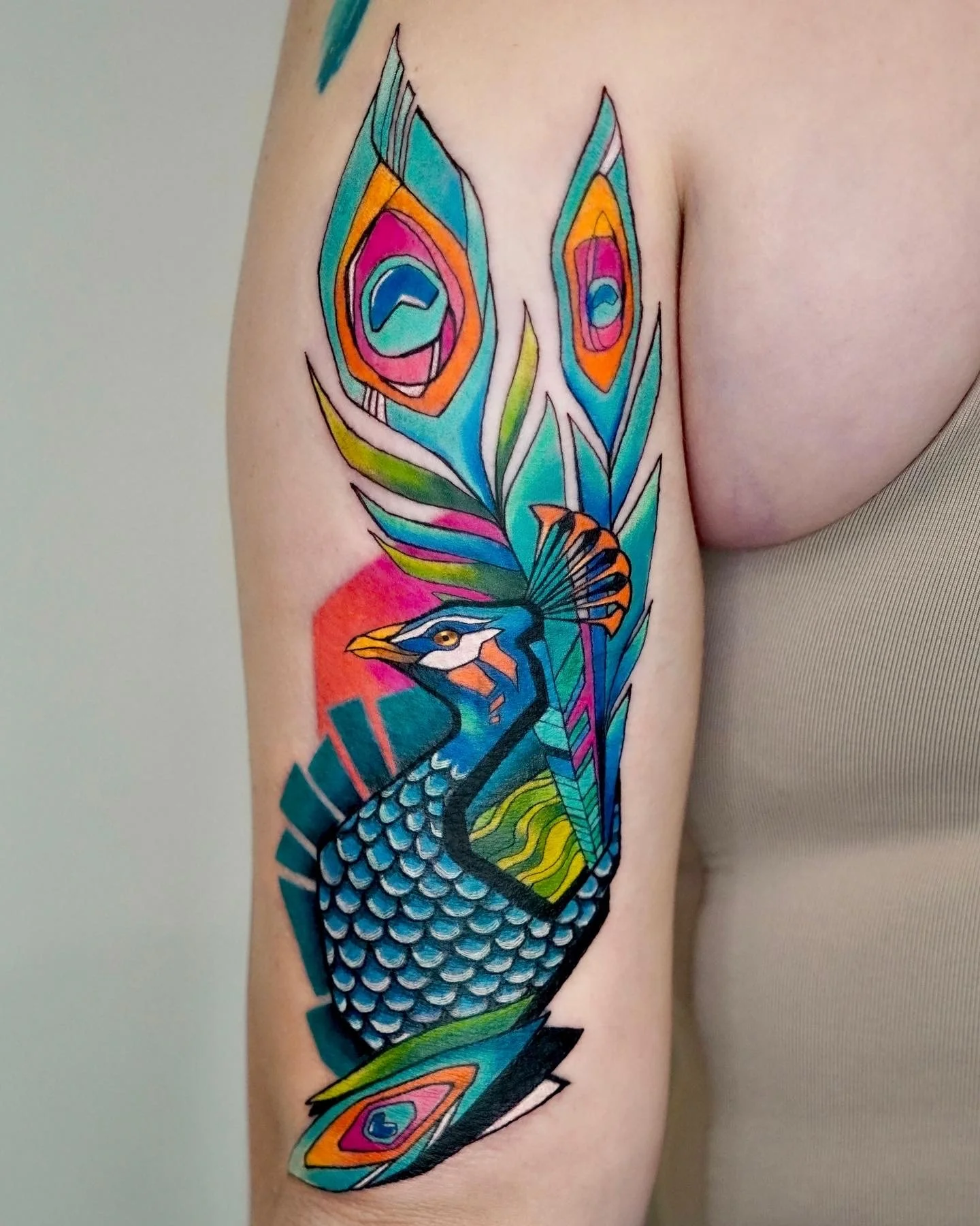 Colorful tattoo of a peacock with vibrant feathers on a person's arm.