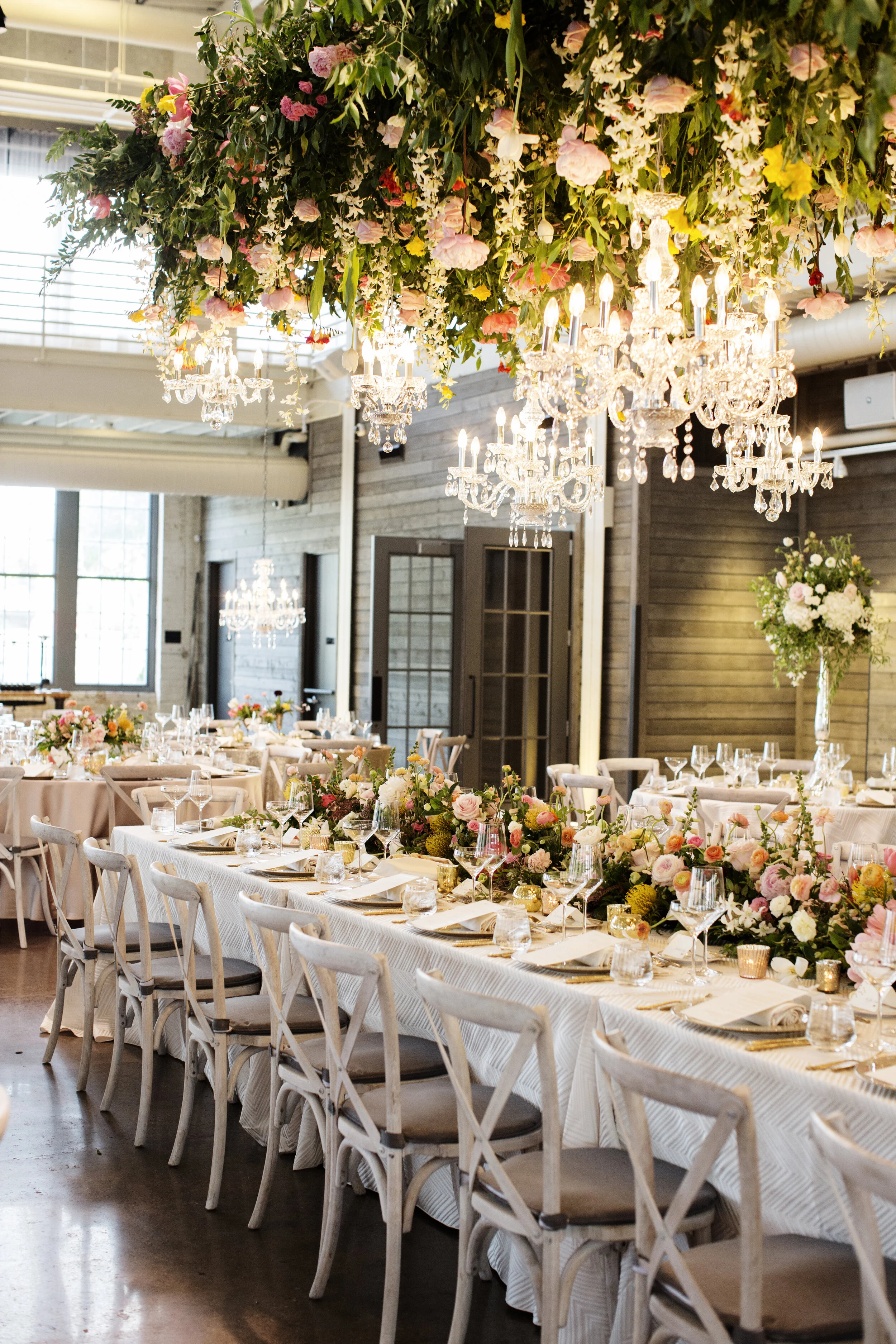 Elegant banquet hall decorated with chandeliers, floral arrangements, and a long dining table set for a formal event.