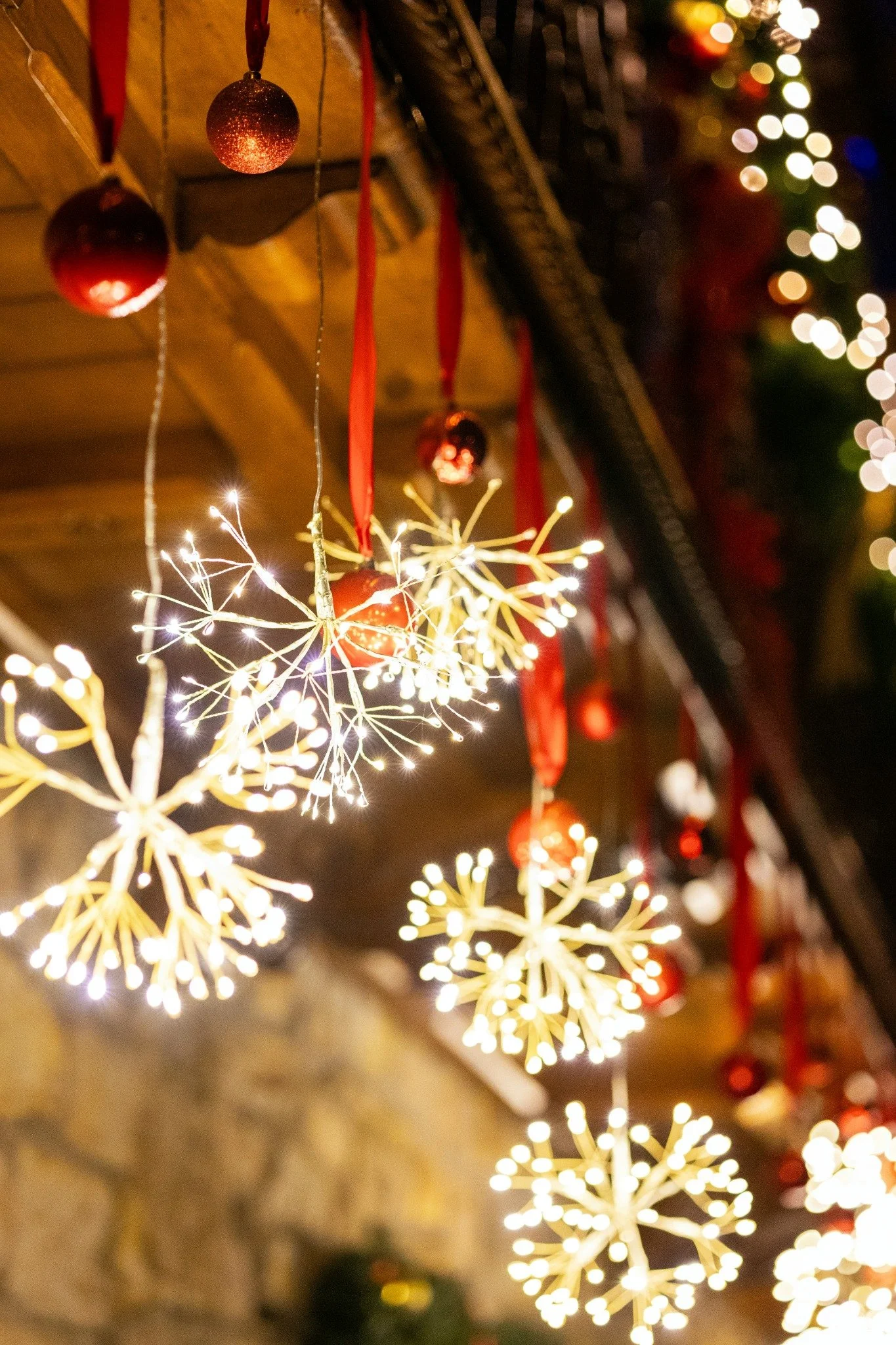 Red hanging ornaments and glowing starburst lights suspended as festive holiday décor.
