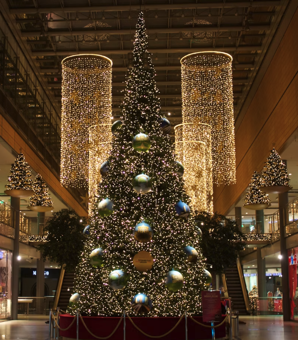 Warm white curtain lights and a decorated Christmas tree illuminating an elegant hotel-style lobby.