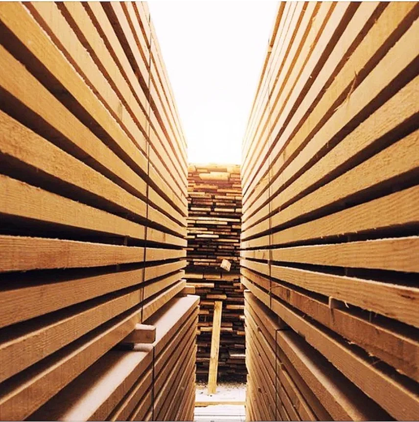 Stacks of wooden planks arranged closely together in a lumber yard.