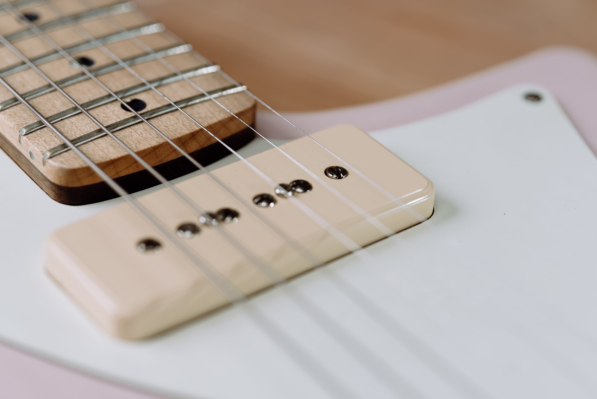 Close-up of electric guitar strings and pickup.