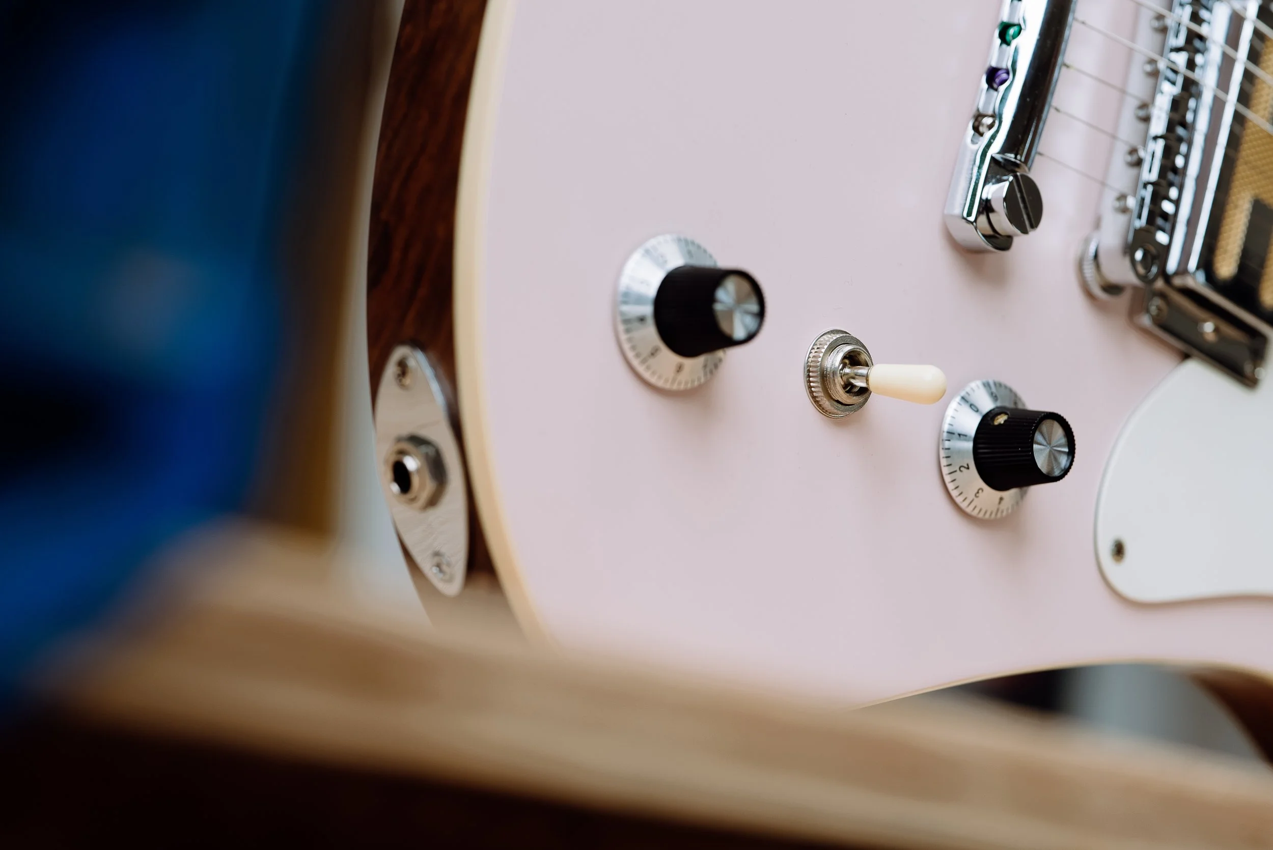 Close-up of electric guitar controls, including knobs and a toggle switch.