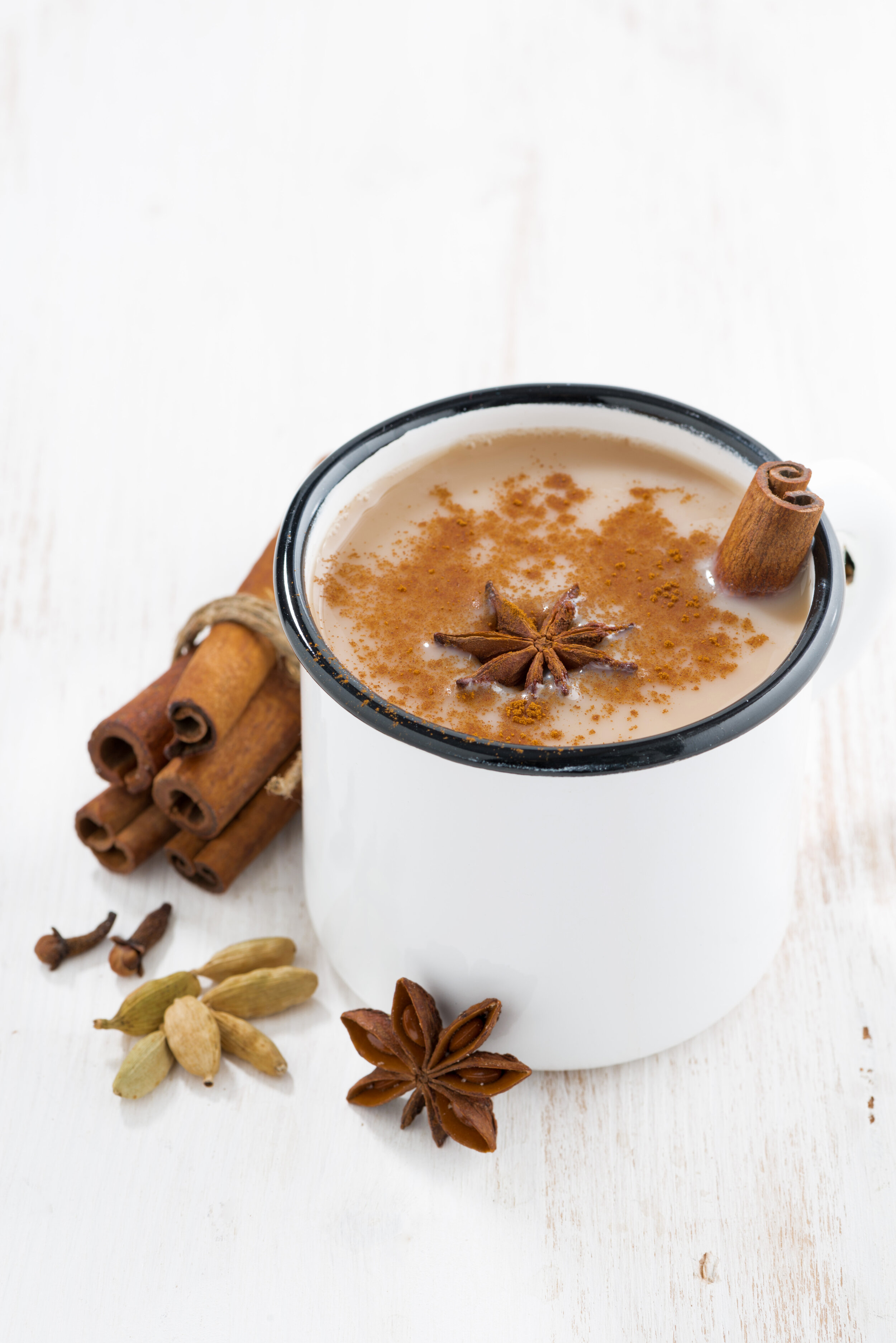 Masala-tea-in-cup-and-ingredients-on-white-table,-vertical-607476976_4817x7217.jpeg