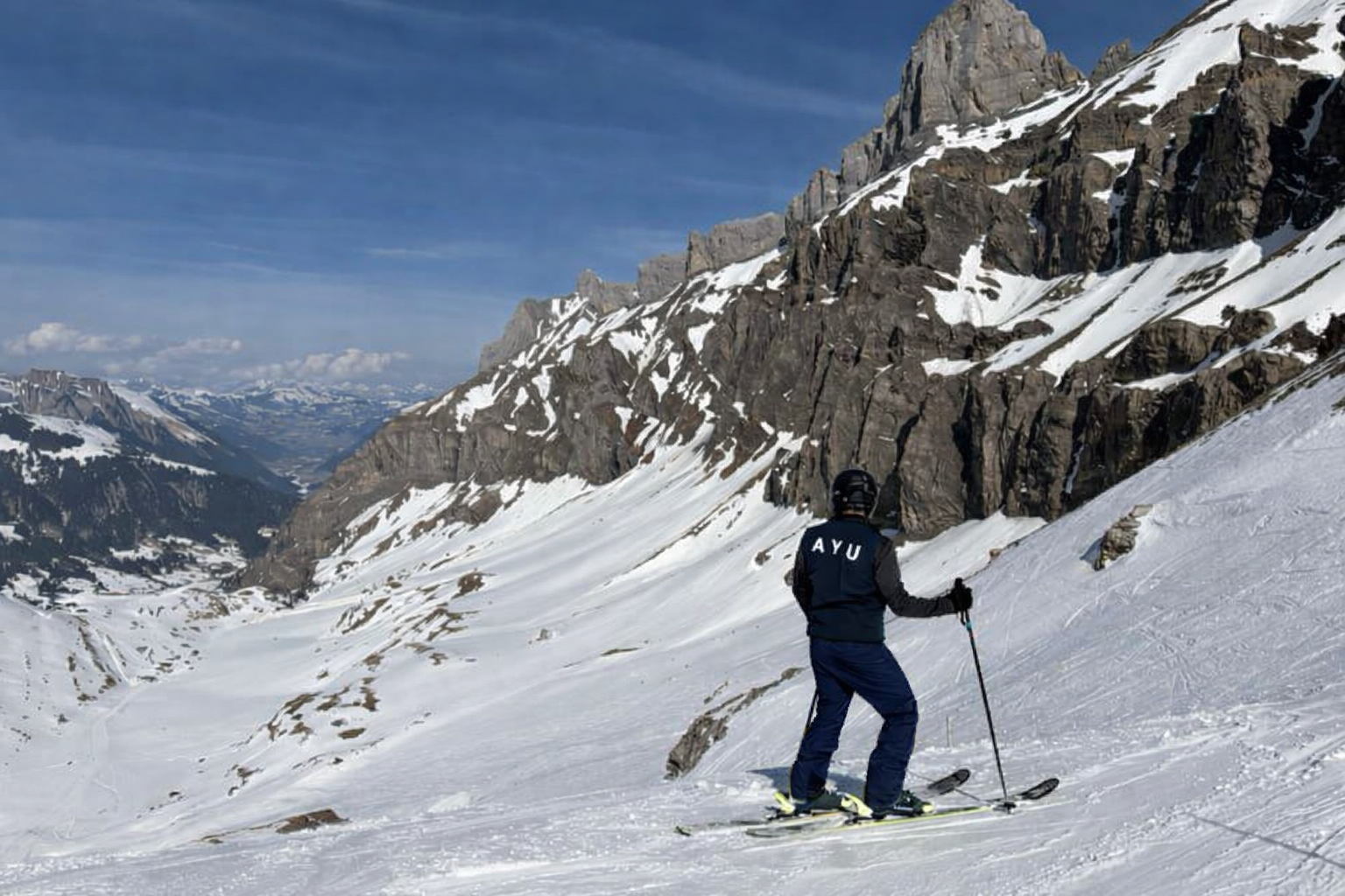 Skier overlooking snowy Swiss Alps view.png