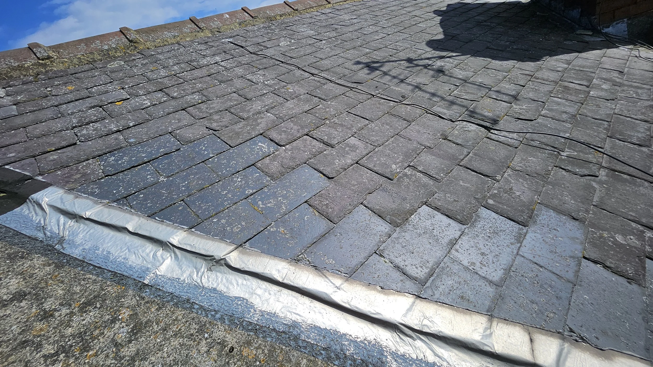Deteriorated roof with new tiles being installed in the lower left corner.