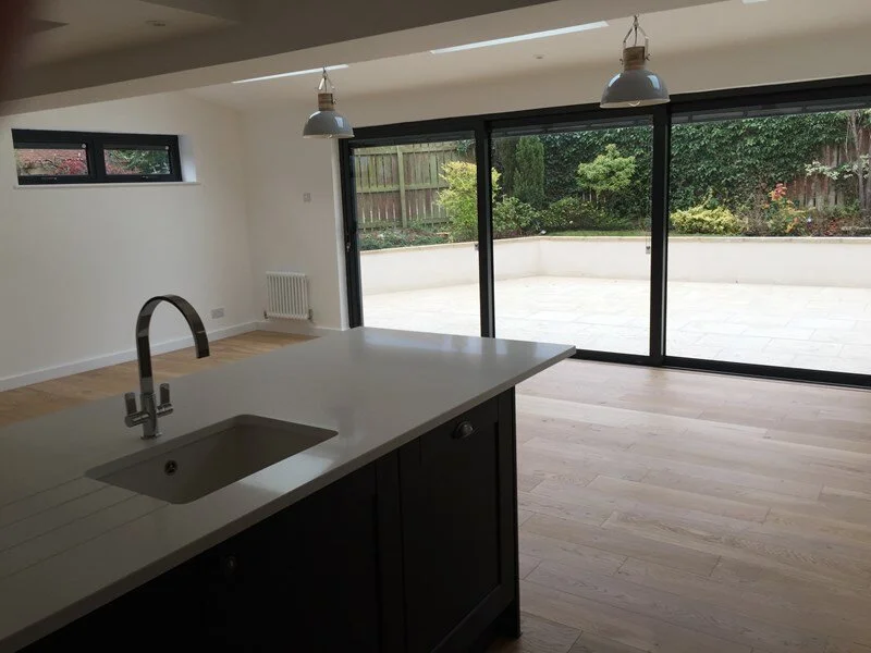 Modern open-concept kitchen and dining area with large sliding glass doors leading to an outdoor patio, minimal decor, and natural light.